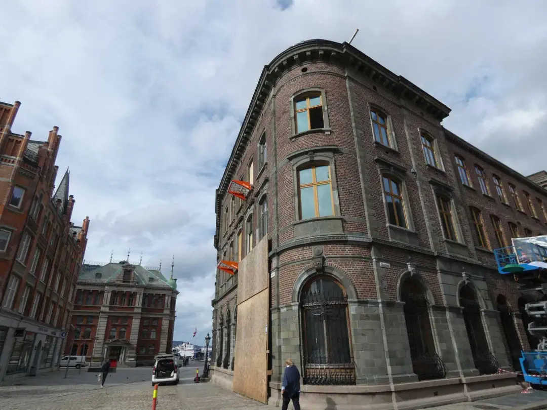 Historic brick corner building with ground floor hoarding and access plant on a city street